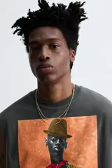 Camiseta sin mangas gris oscuro de corte holgado, con cuello redondo y estampado frontal de un hombre con sombrero y camisa floreada. Diseño de la colaboración especial Zara x Otis Kwame Kye Quaicoe.