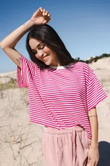 Remera de algodón a rayas horizontales blancas y fucsias, con cuello redondo y mangas cortas.