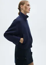 Chaqueta bomber azul marino con diseño crop, cuello alto, cierre delantero con cremallera, dos bolsillos laterales, diseño recto, oversize y manga larga.