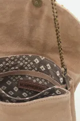 Cartera de mano negra de cuero gamuzado con solapa bordada con diseño de alas en tonos dorados y plateados. Tiene cierre magnético, bolsillos internos y cadena metálica dorada vieja.