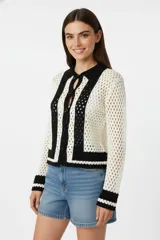 Cardigan de algodón con punto crochet calado, corte ancho, con botones, cuello tipo camisa y mangas largas. Diseño a rayas verticales en blanco y negro.