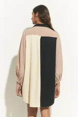 Túnica corta de algodón con cuello clásico y mangas largas. Presenta un diseño de bloques de color en negro, beige y rosa pálido.
