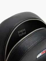 Mochila negra de poliuretano con acabado granulado, logo engomado de Tommy Jeans en el frente, asa superior, correas ajustables y bolsillo exterior con cremallera.