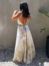 Vestido largo de tela fluida, color verde esmeralda con estampado abstracto en tonos turquesa y detalles dorados. Diseño asimétrico con un solo tirante tejido en el hombro.