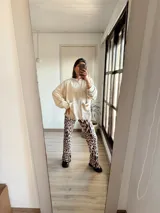 Campera oversize color crudo con mangas largas abullonadas y bolsillo frontal. Pantalón palazzo con estampado animal print.