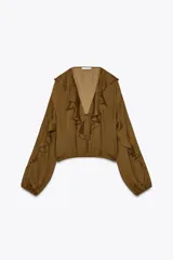 Blusa color marrón con escote en pico, manga larga abullonada con elástico en los puños y volantes en el escote y mangas.