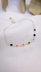 Pulsera de plata 925 con cadena de eslabones y siete dijes redondos con engarce de piedras de diferentes colores representando los 7 chakras.