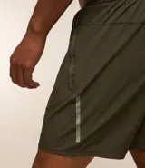 Bermuda deportiva negra sin estampado, con cintura elástica ajustable con cordón, y bolsillo lateral con cierre de cremallera contrastante.