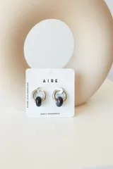 Aros de acero quirúrgico hipoalergénico con forma de argolla plateada y dije circular colgante de piedra natural color azul.