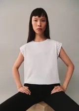 Camiseta gris de algodón con cuello redondo y mangas cortas con tachas plateadas en los hombros.