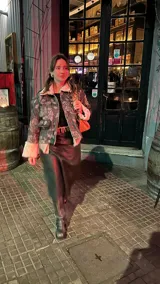 Chaqueta corta gris con estampado de rosas negras, cuello y puños de piel sintética blanca, cierre frontal con cremallera y bolsillos delanteros con solapa.