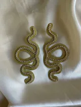 Par de aros colgantes con forma de serpiente contorneada en strass y cierre a presión de acero inoxidable.