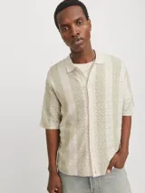 Polo de manga corta color crema con rayas verticales en relieve color verde claro. Tiene cuello clásico y cierre frontal con botones.