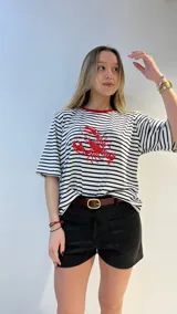 Remera oversize a rayas horizontales blancas y negras con cuello rojo y estampado de langosta roja. Corte holgado y mangas cortas.