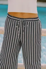 Pantalón de tiro medio con cintura elástica ajustable con cordones, bolsillos delanteros y traseros de parche. Pierna ancha con estampado de rayas verticales azules y blancas.