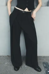 Pantalón negro de tiro medio con cinturón a tono con hebilla metálica, bolsillos delanteros y falsos bolsillos traseros.