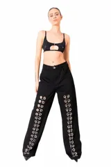 Pantalón de jean negro de corte ancho con detalle de ojalillos metálicos en los laterales.