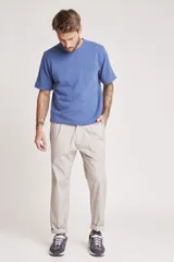 Pantalón de vestir color beige, de corte recto, con bolsillos laterales y traseros. Se ajusta a la cintura con cinturón de cuero marrón.