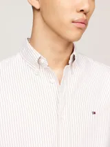 Camisa de algodón Oxford a rayas verticales blancas y beige, de corte regular, con cuello abotonado, mangas largas con puños abotonados y logo de Tommy Hilfiger bordado en el pecho.