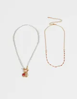 Set de dos collares dorados: uno de cadena con mostacillas rojas y otro de perlas con cierre marinero y dijes de vaquita de San Antonio, cerezas y perla.