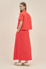 Falda larga color coral, estilo cargo, con cintura regulable con cordón, tajo frontal y bolsillos laterales con solapa.