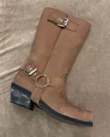 Bota alta de cuero vacuno color negro, con caña recta, punta cuadrada y estribo desmontable.