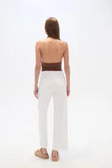 Pantalón blanco de algodón, corte recto y tiro medio, con bolsillos laterales y cierre frontal con cremallera.