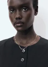 Chaleco negro con cuello redondo, sin mangas y cierre frontal con botones.