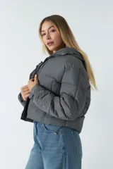 Campera puffer corta color negro con capucha, cierre metálico y botones a presión. Cuenta con bolsillos laterales invisibles con cierre.