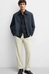 Pantalón chino color beige, corte recto, con bolsillos laterales y traseros. Cierre frontal con cremallera y botón.