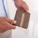 Billetera negra de símil cuero con banda elástica horizontal blanca. Interior con doble compartimento para billetes, visor y tarjeteros.