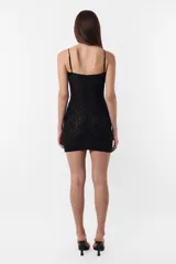 Vestido corto de encaje negro con breteles finos regulables y abertura circular en el escote.