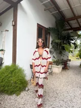 Camisa de tejido de punto oversize con botones en el frente y diseño a rayas horizontales en tonos beige, rojo, marrón y celeste.