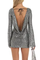 Vestido corto plateado de lentejuelas con mangas largas acampanadas y espalda descubierta que se ata con tiras.