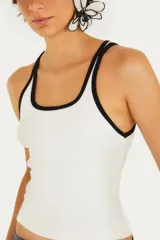 Musculosa negra con tirantes finos y ribete blanco, escote recto y corte ajustado.