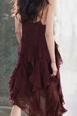 Vestido midi de viscosa color borgoña, con escote en V, tirantes finos ajustables, bordados a tono y volantes en el mismo tejido. El bajo es asimétrico.