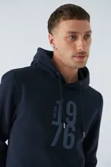 Buzo canguro color marrón con capucha ajustable, bolsillo canguro, fit regular, arte estampado en relieve y logo en goma.