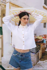 Camisa blanca de lino con cuello y puños de crochet color beige, manga larga y cierre con botones color madera.