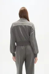 Campera gris de manga larga con cierre frontal, cuello alto y vivos blancos en los hombros y mangas.