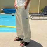 Pantalón cargo de lino color blanco, corte holgado (oversize), con cordón ajustable en la cintura y bolsillo cargo con etiqueta en el lateral del muslo.