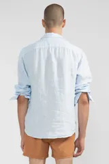 Camisa celeste de lino con botones de coco y corte recto.