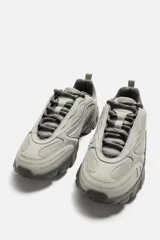 Zapatillas grises con cordones, capellada combinada y suela chunky con diseño irregular.
