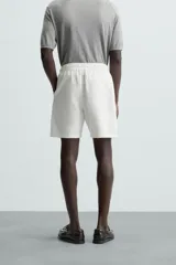 Bermuda de algodón color marrón oscuro, de corte regular fit, con cintura elástica ajustable mediante cordón. Presenta bolsillos laterales y un bolsillo trasero de vivo.