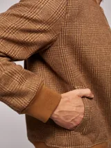 Campera bomber marrón con estampado a cuadros, cuello, puños y ruedo acanalados. Cierre frontal con cremallera.