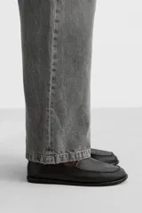 Mocasín negro de piel con construcción desestructurada y suela fina.