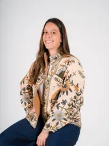 Chaqueta color crema con bordados florales en tonos azules, verdes y marrones, con cuello mao y cierre frontal con cremallera.