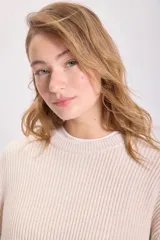 Sweater color crudo de punto inglés con cuello redondo y mangas largas.