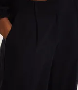 Pantalón de vestir negro, de corte recto, con bolsillos laterales y traseros. Se ajusta a la cintura con cinturón de cuero marrón.