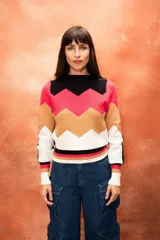 Sweater de punto con diseño geométrico en bloques de color negro, fucsia, beige y blanco.