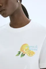 Remera blanca de corte holgado en punto de algodón. Modelo con cuello redondo y estampado de limones con texto en el frente.
